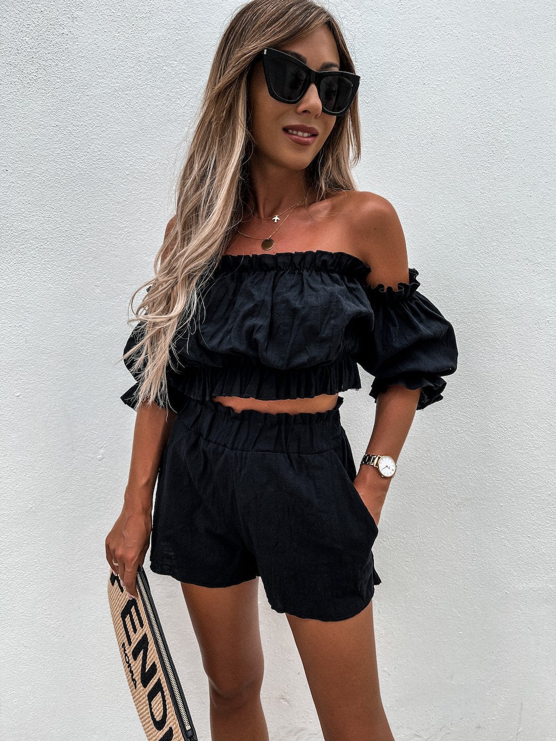 Model staand met zwarte Tweedelige linnen set met off the shoulder top